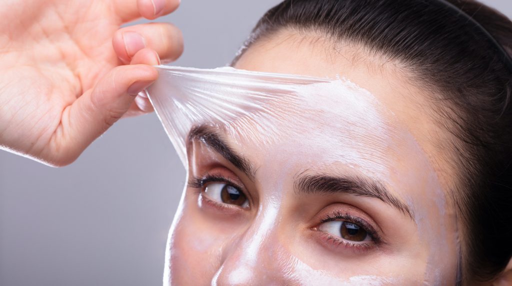 Woman peeling substance off her face