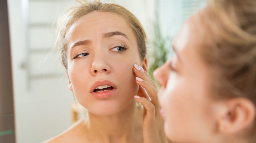 Woman inspecting her face for skin cancer