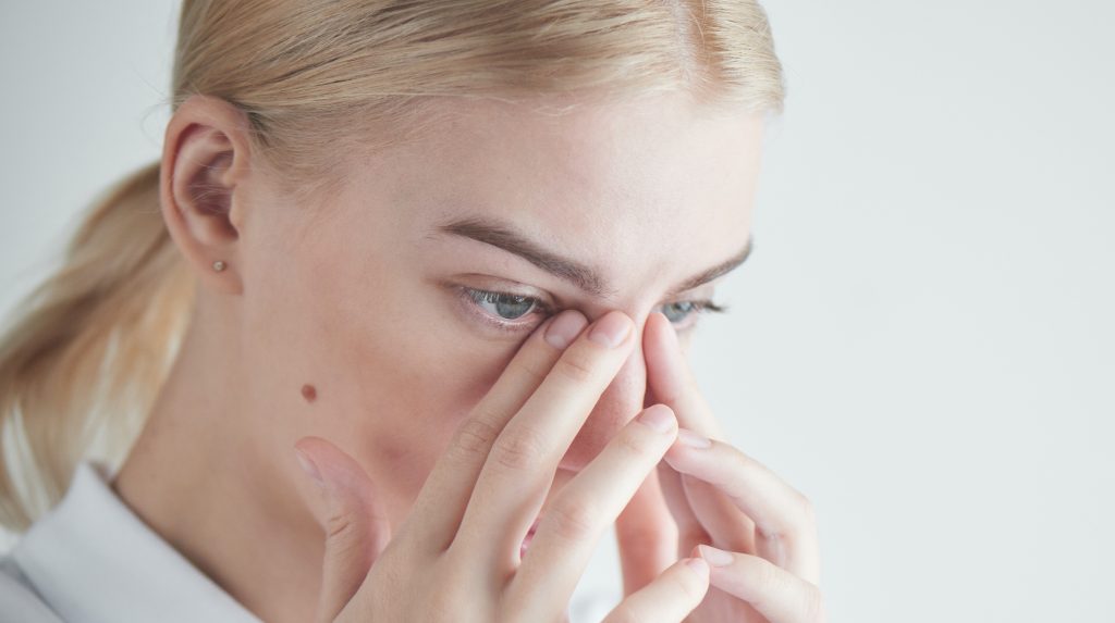 Blonde woman placing her hands on her nose